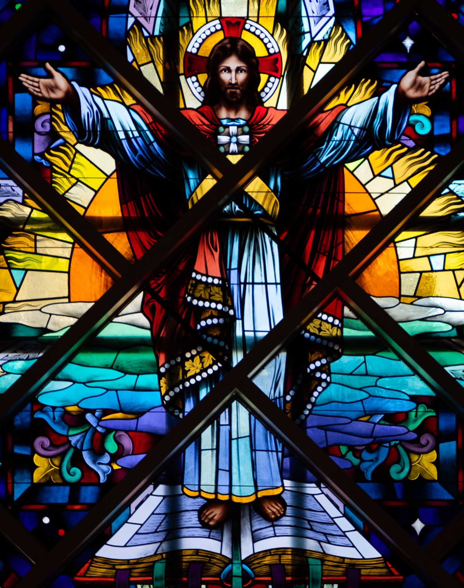 Stained glass window of Jesus standing on a Bible.