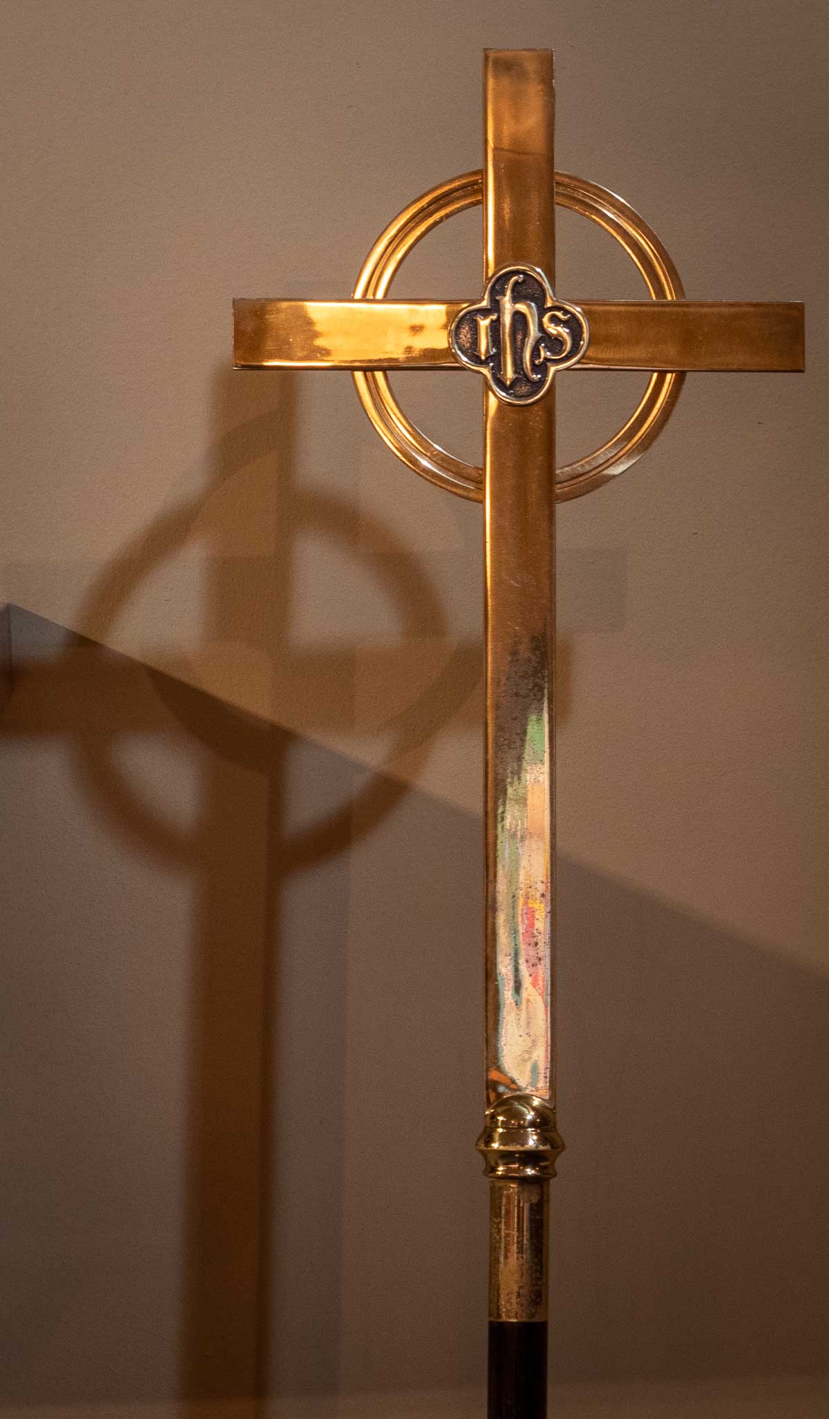 A brass cross with a shadow behind it.