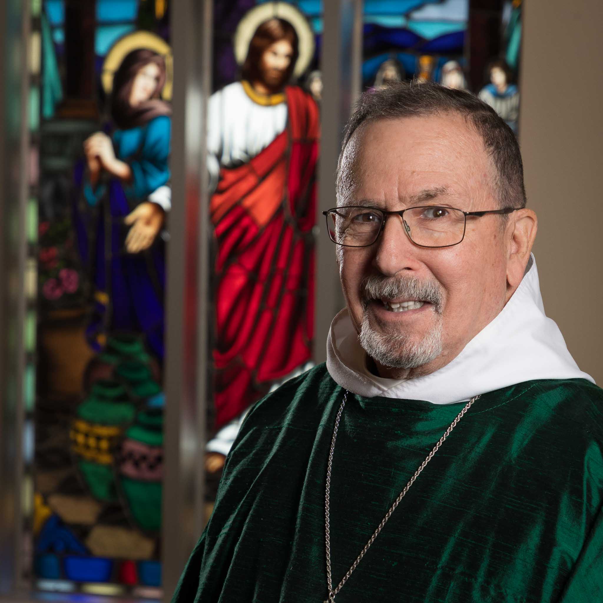 Rev. Tom Carter in front of a stained glass window.
