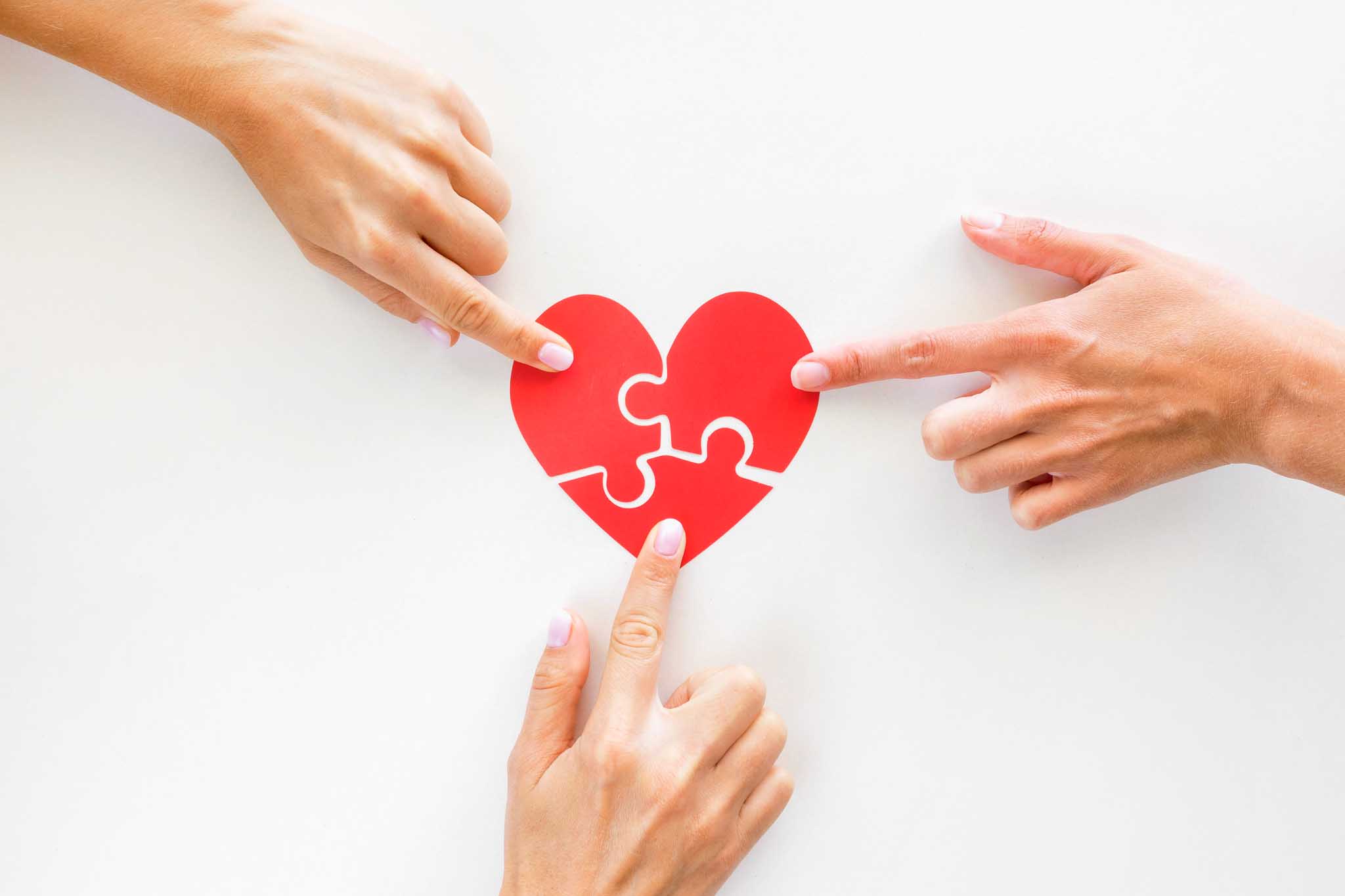 Hands touching a heart puzzle.