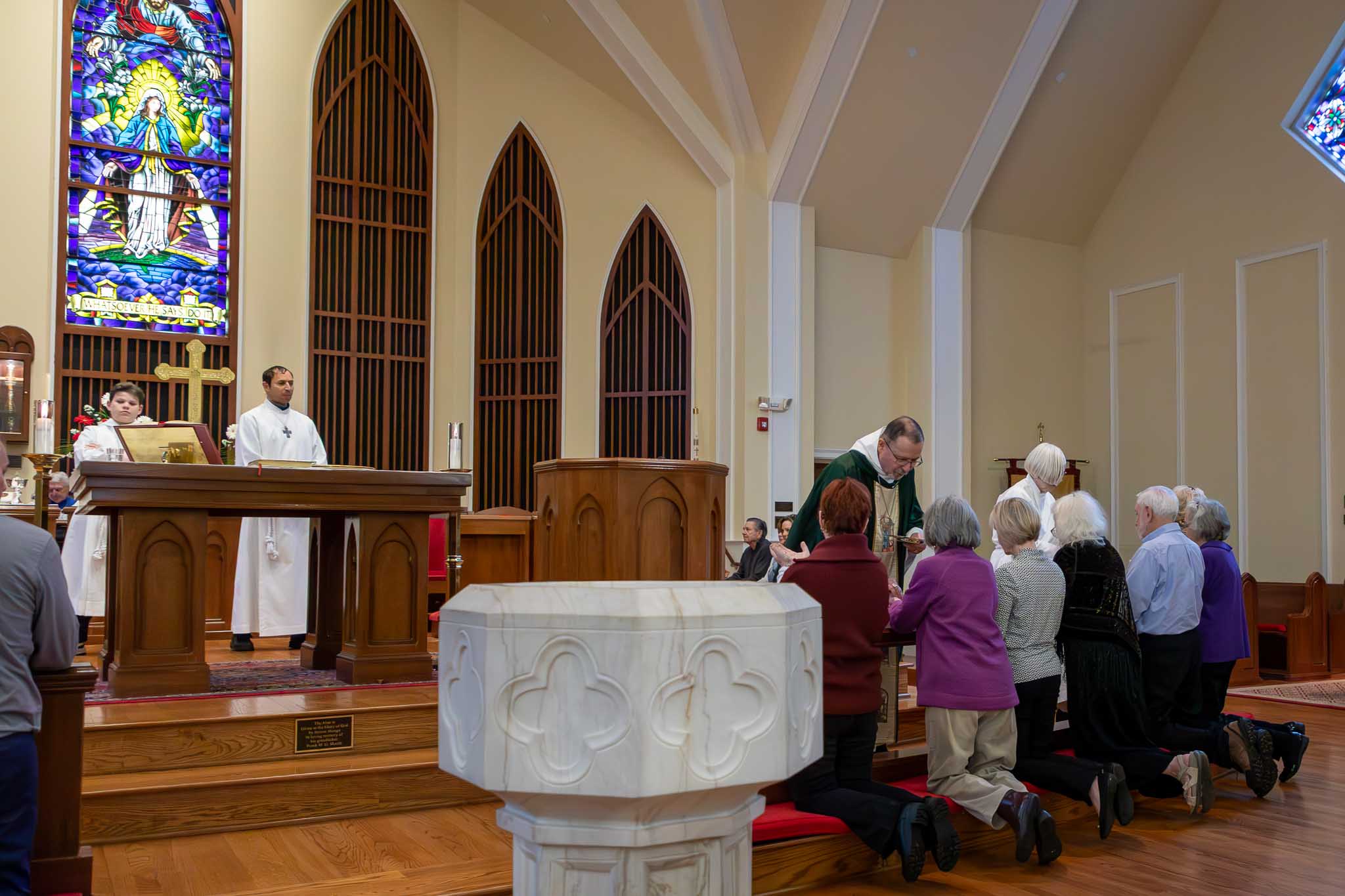 Minister and server giving communion to parishioners.